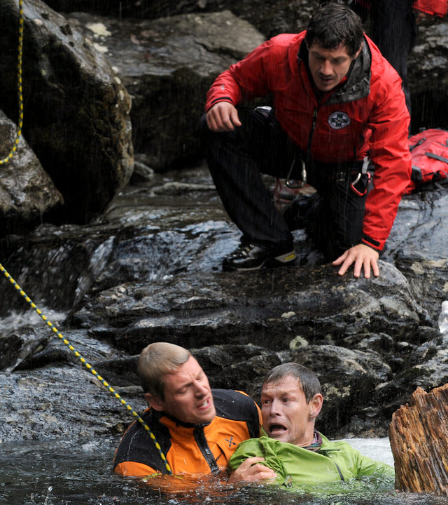 "Die Bergretter - Jetzt oder nie": Andreas (Martin Gruber) und Thomas (Steffen Wink) sind im Wasser. Andreas hält Thomas am Arm fest. Über ihnen, auf einem Fels, kniet Tobias (Markus Brandl).
