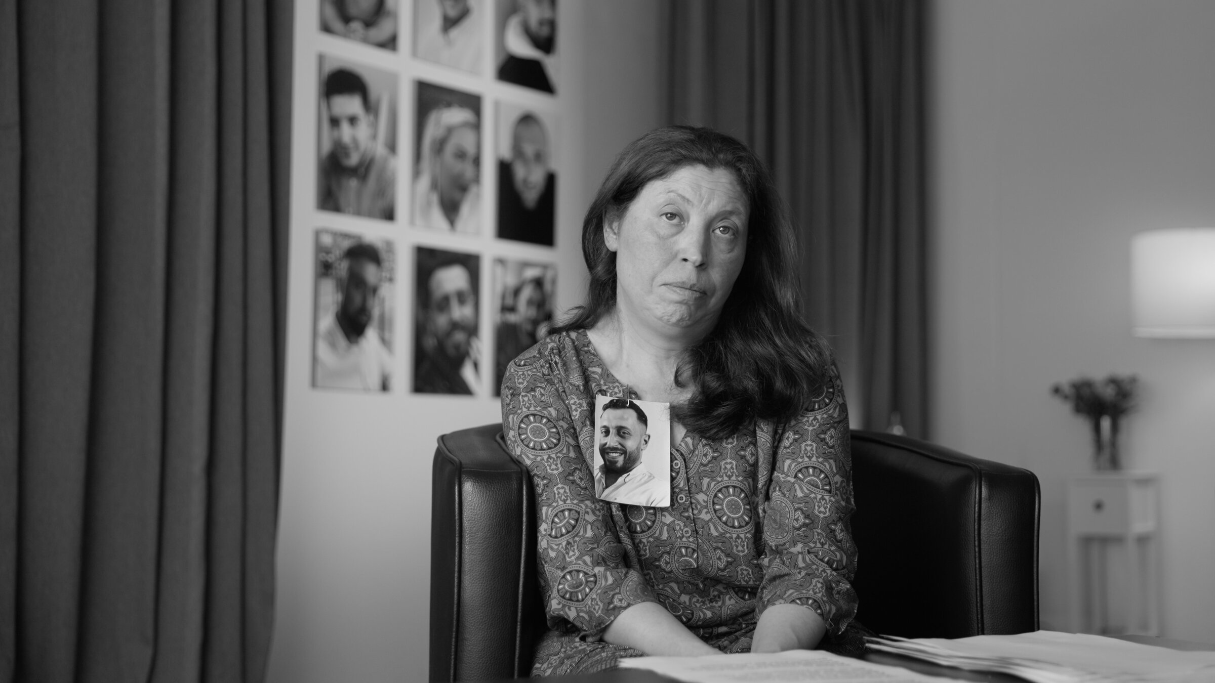 "Das Deutsche Volk": Frau blickt direkt in die Kamera. An ihrem Revers ist das Foto eines jungen Mannes befestigt.