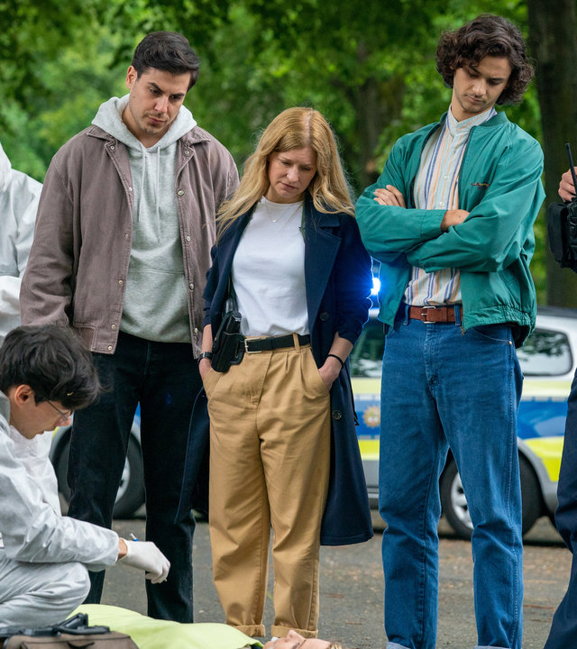 "Blutige Anfänger - Wut": Umut (Uğur Ekeroğlu), Koko (Birte Hanusrichter), Bruno (Martin Peñaloza Cecconi) und Phillip (Erik Cordes) stehen nebeneinander auf einer Straße. Alle blicken auf den Boden. Dort liegt Michelle Listing (Janine Theisen). Sie ist tot. Neben ihr in der Hocke sitzt Leon Landsberg (Florian Clyde). Er trägt einen weißen Overall der Spurensicherung und Handschuhe.
