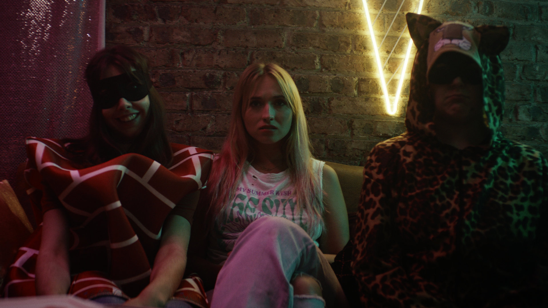 "Derby Girl - Jetzt erst recht": Lola (Chloé Jouannet), Absinthe (Suzanne De Baecque) und MJ (Salomé Diénis Meulien) sitzen gemeinsam auf einer Couch in einem dunkeln Keller. Während Absinthe und MJ ein Kostüm tragen, sitzt Lola ohne Verkleidung zwischen den beiden und schaut entmutigt drein.