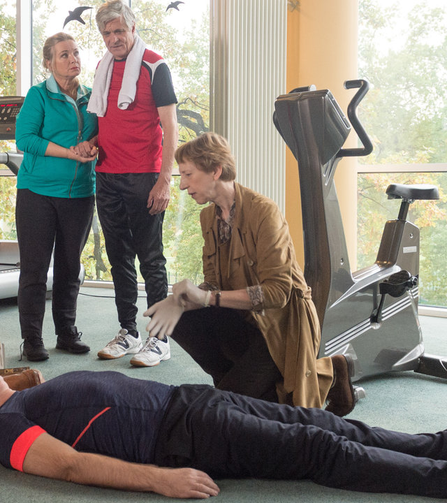 „SOKO Wismar – Fit für die Ewigkeit“: Im Fitnessraum liegt Markus Rotmanns (Herbert Trattnigg) lebloser Körper  am Boden. Um ihn herum sind Rechtsmedizinerin Helene Sturbeck (Katharina Blaschke) und Kommissar Lars Pöhlmann (Dominic Boeer), im Hintergrund stehen Hans (Dietrich Adam) und Elisabeth Güstrow (Susanne Bentzien).