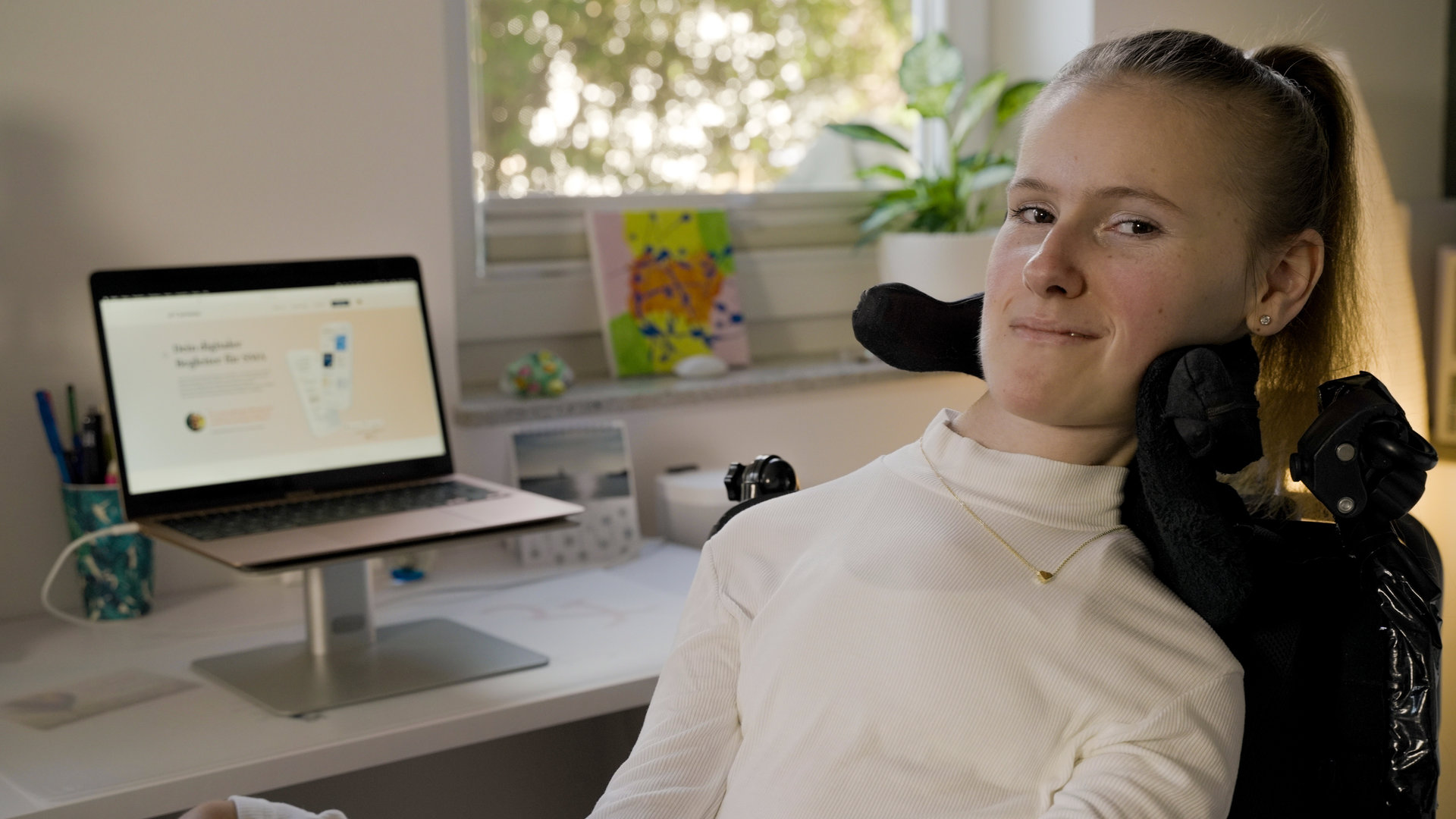 "einfach Mensch: Sina Wolf: Mein Engagement ist mir wichtig!": Sina Wolf sitzt vor einem Schreibtisch mit einem Laptop.