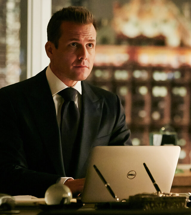 "Suits - Das Versprechen": Harvey (Gabriel Macht)  sitzt am Schreibtisch vor seinem aufgeklappten Laptop und schaut interessiert. Im Hintergrund sind die bei Abend erleuchteten Hochhäuser New Yorks zu erkennen.