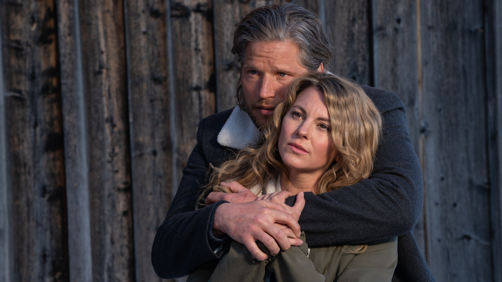 "Die Bergretter: Dieses eine Leben": Vor einem Holztor steht Markus (Sebastian Ströbel) und hat die Arme um Katharina (Luise Bähr) gelegt, die vor ihm steht und nicht unglücklich wirkt.