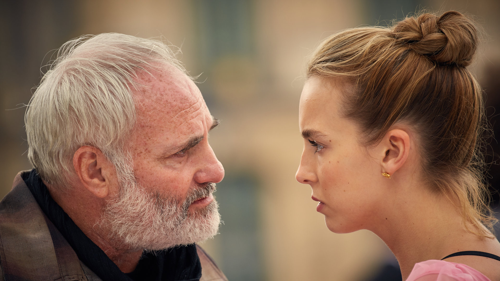 "Killing Eve – Ihn werde ich später los“: Villanelle (Jodie Comer) und Konstantin (Kim Bodnia) stehen sich auf einem öffentlichen Platz gegenüber und schauen sich ernst an.
