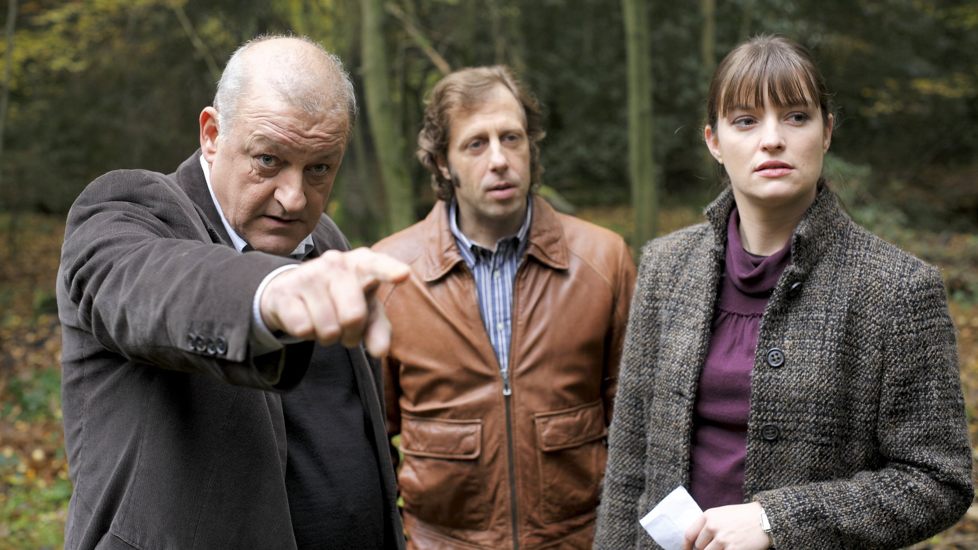 "Wilsberg - Bullenball": Georg Wilsberg (Leonard Lansink), Ekki Talkötter (Oliver Korittke) und Alex Holtkamp (Ina Paule Klink) suchen etwas im Wald.