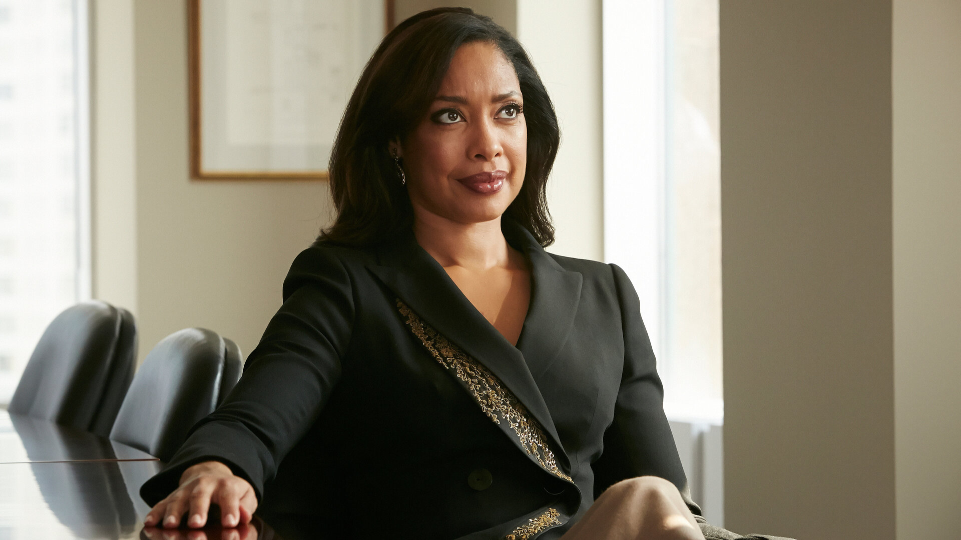 "Suits - Wie du mir, so ich dir": Jessica (Gina Torres) sitzt, elegant gekleidet, an ihrem Schreibtisch und schaut selbstbewusst nach vorne. Sie hat ihre rechte Hand auf den Schreibtisch gelegt.
