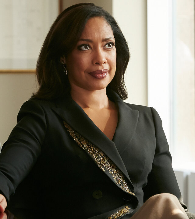"Suits - Wie du mir, so ich dir": Jessica (Gina Torres) sitzt, elegant gekleidet, an ihrem Schreibtisch und schaut selbstbewusst nach vorne. Sie hat ihre rechte Hand auf den Schreibtisch gelegt.