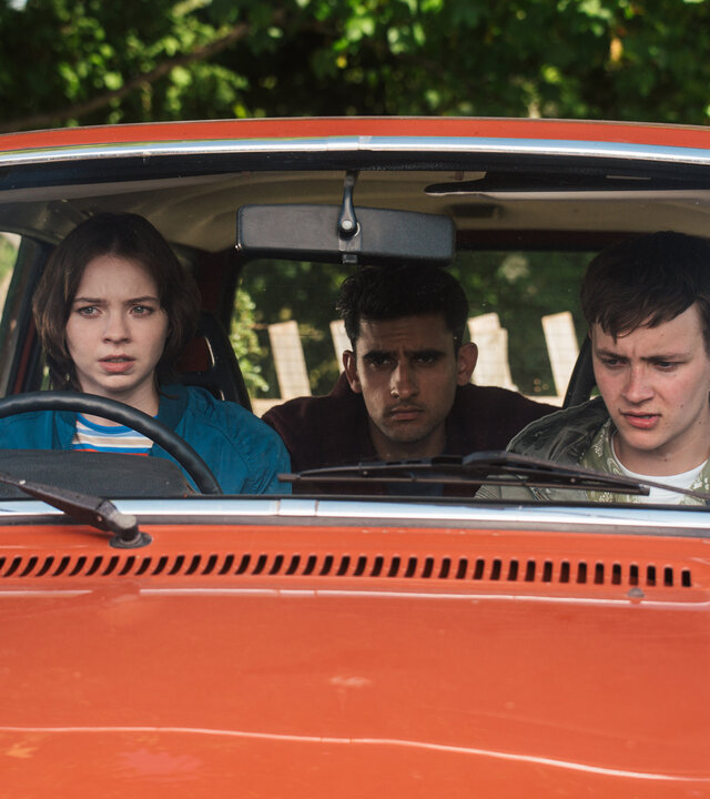 "A Good Girl’s Guide to Murder – Wie man einen Catfish angelt": Pip Fitz-Amobi (Emma Myers) sitzt am Steuer eines roten Autos, neben ihr sitzt Connor Reynolds (Jude Morgan-Collie), auf dem Rücksitz Ravi Singh (Zain Iqbal). Alle drei blicken angespannt nach vorn.