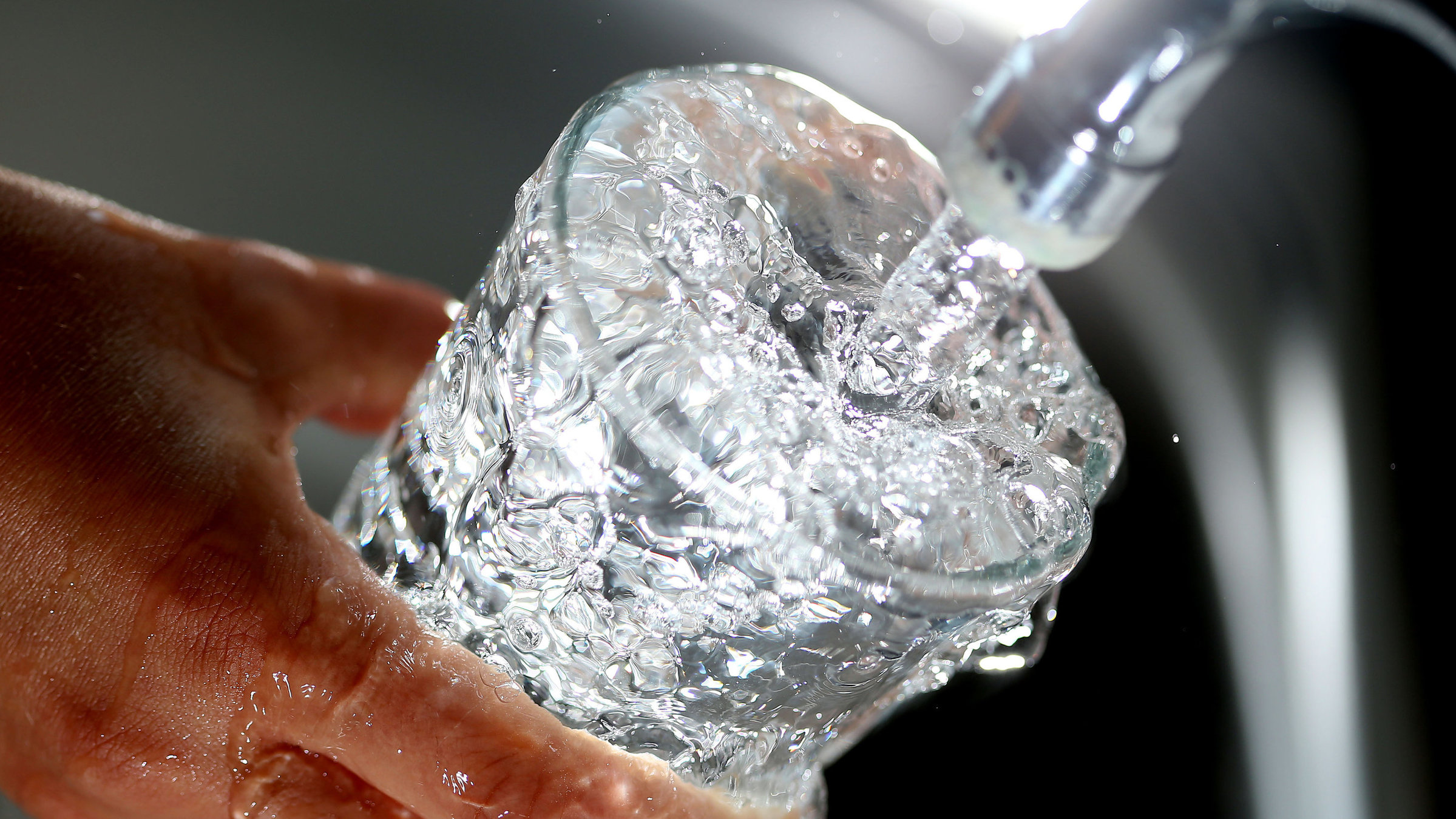 "sonntags - Wasser erhalten": Wasser läuft aus Wasserhahn in ein Glas.