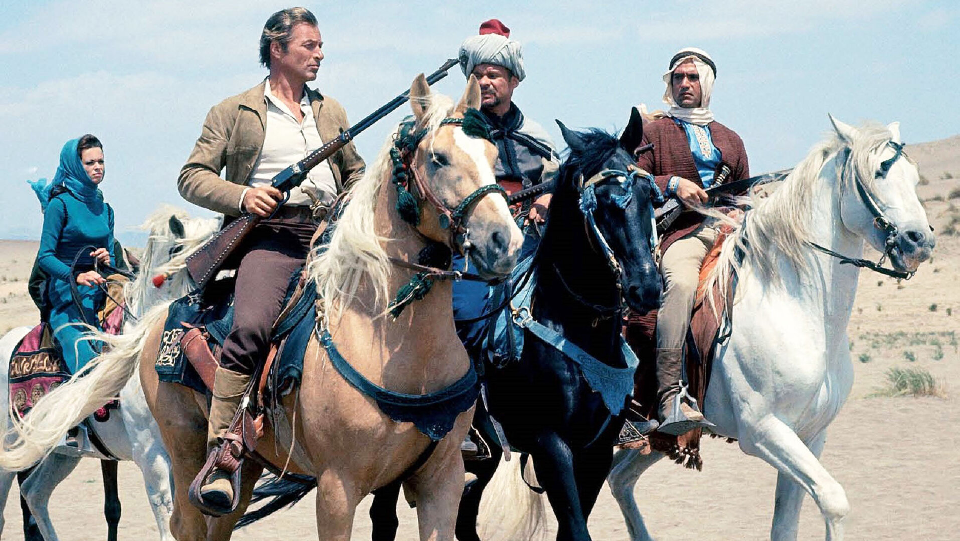 "Im Reiche des Silbernen Löwen": Kara Ben Nemsi (Lex Barker), Ingdscha (Marie Versini), Hadschi Halef Omar (Ralf Wolter) und Ahmed el Corda (Gustavo Rojo) reiten auf Pferden durch die Wüste.