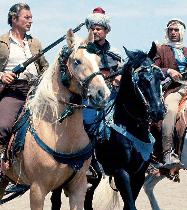 "Im Reiche des Silbernen Löwen": Kara Ben Nemsi (Lex Barker), Ingdscha (Marie Versini), Hadschi Halef Omar (Ralf Wolter) und Ahmed el Corda (Gustavo Rojo) reiten auf Pferden durch die Wüste.