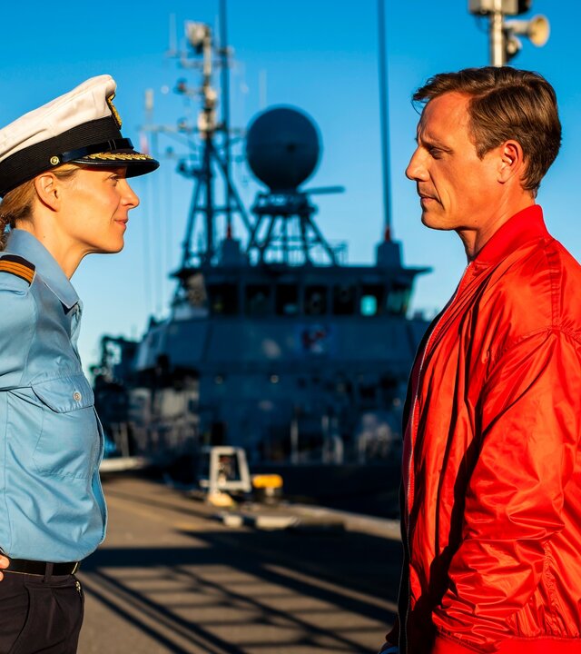 "Dr. Nice - SchiffbrÃ¼chig": Im Hafen steht die Marineoffizierin Miriam Nicolai (Franziska Junge) Dr. Nice (Patrick Kalupa) gegenÃ¼ber. Sie hat ihre HÃ¤nde in die HÃ¼ften gestemmt.