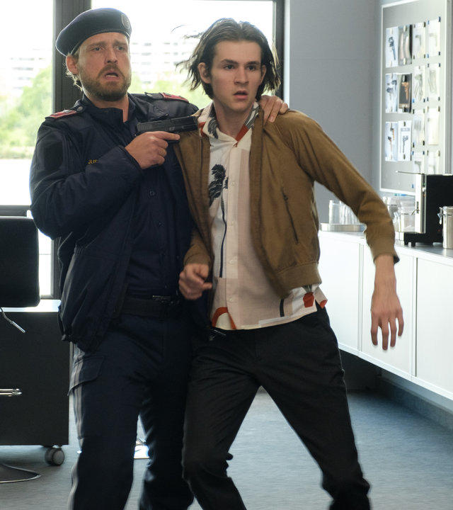 "SOKO Wien - Grenzen": Ludwig Pichler (Fabian Schiffkorn) hat Gio Egger (Enzo Gaier) im Kommissariat an der Schulter gepackt und hält ihm eine Waffe an den Hals.
