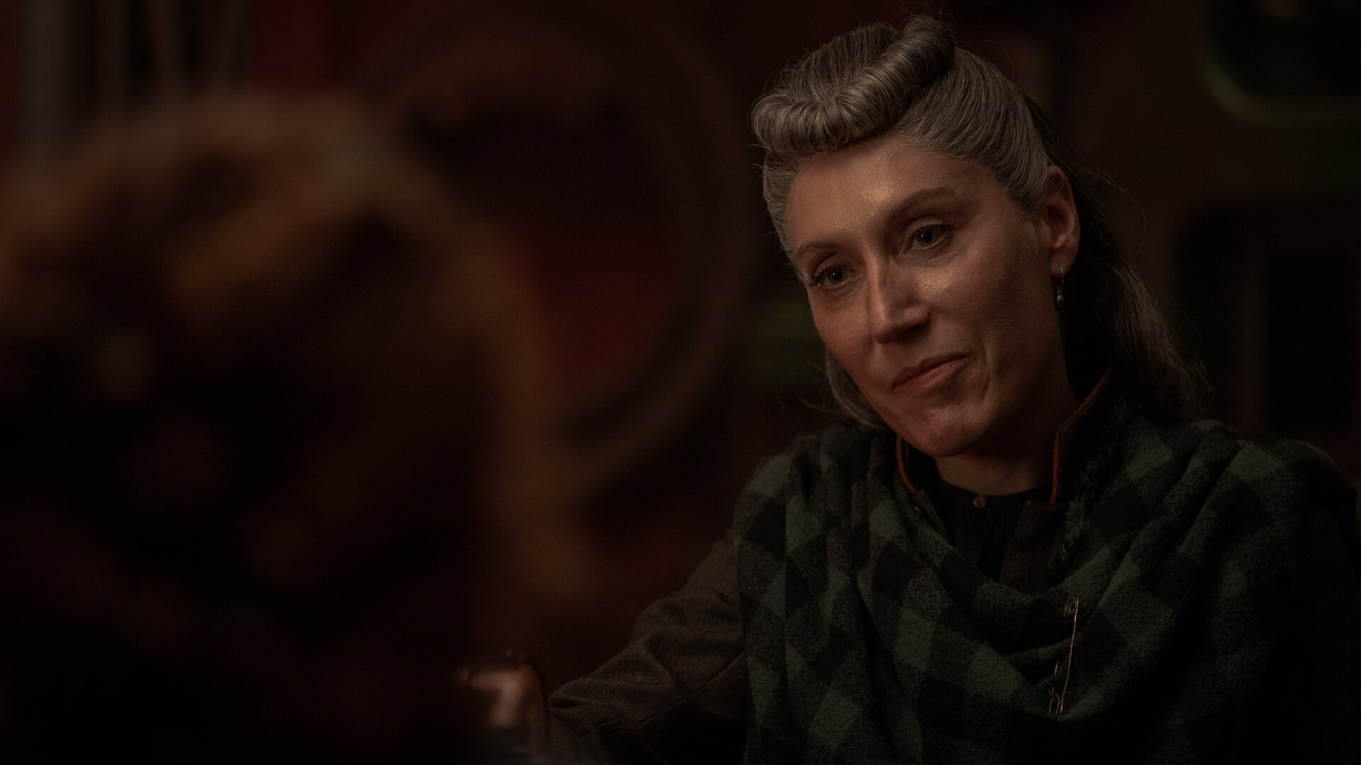 "Nautilus - Am Abgrund": Loti (Céline Menville) befindet sich in einem dunklen Raum. Sie blickt ihr Gegenüber an. Im Vordergrund ist unscharf der Hinterkopf von Humility (Georgia Flood) zu erkennen.