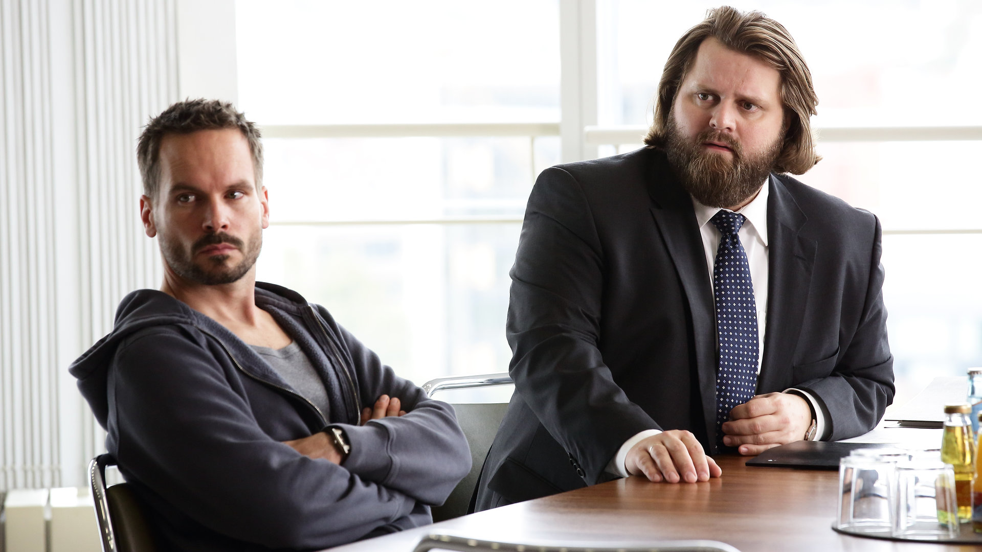 "Ein Fall für zwei - Verhängnisvolle Freundschaft": Leo Oswald (Wanja Mues) und Benni Hornberg (Antoine Monot, Jr.) sitzen an einem Bürotisch und blicken erstaunt in eine Richtung.
