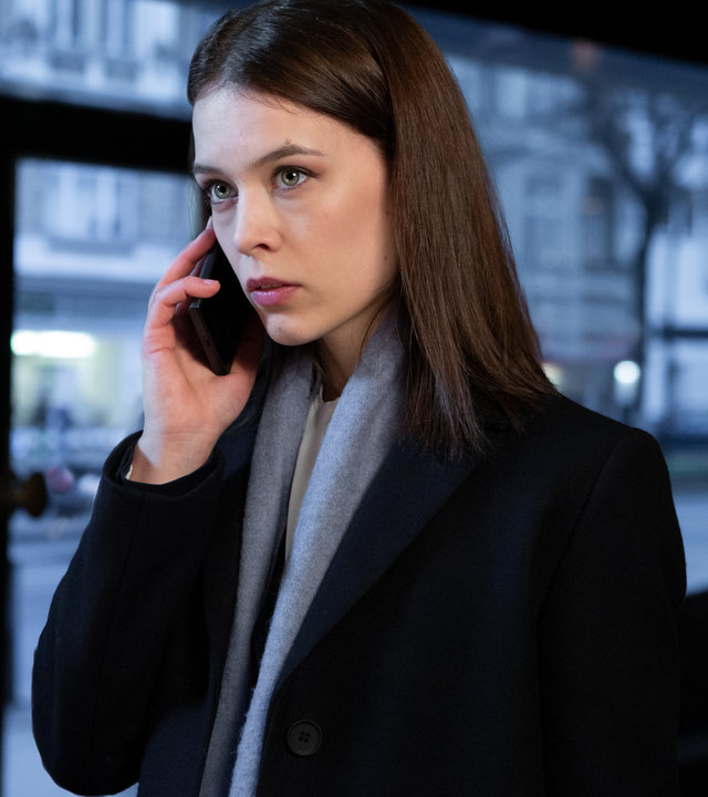 "Bad Banks - Long live the Queen": Jana Liekam (Paula Beer) steht in einem Café und telefoniert. Draußen wird es allmählich dunkel.