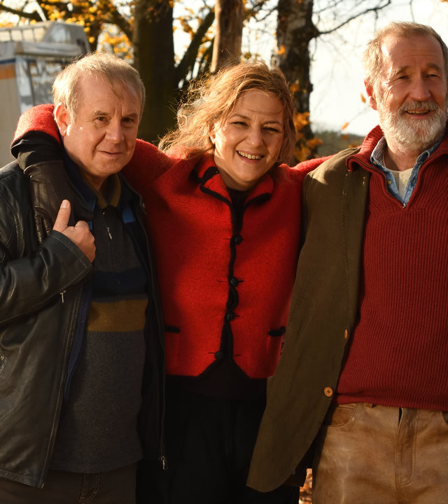 "Endlich Witwer - Forever Young": Auf dem Weg zum Wohnmobil steht Petra Schultheiss (Martina Gedeck) zwischen Georg Weiser (Joachim Król), ) und Jürgen König (Peter Lohmeyer) und stützt sich mit den Armen auf deren Schultern ab.