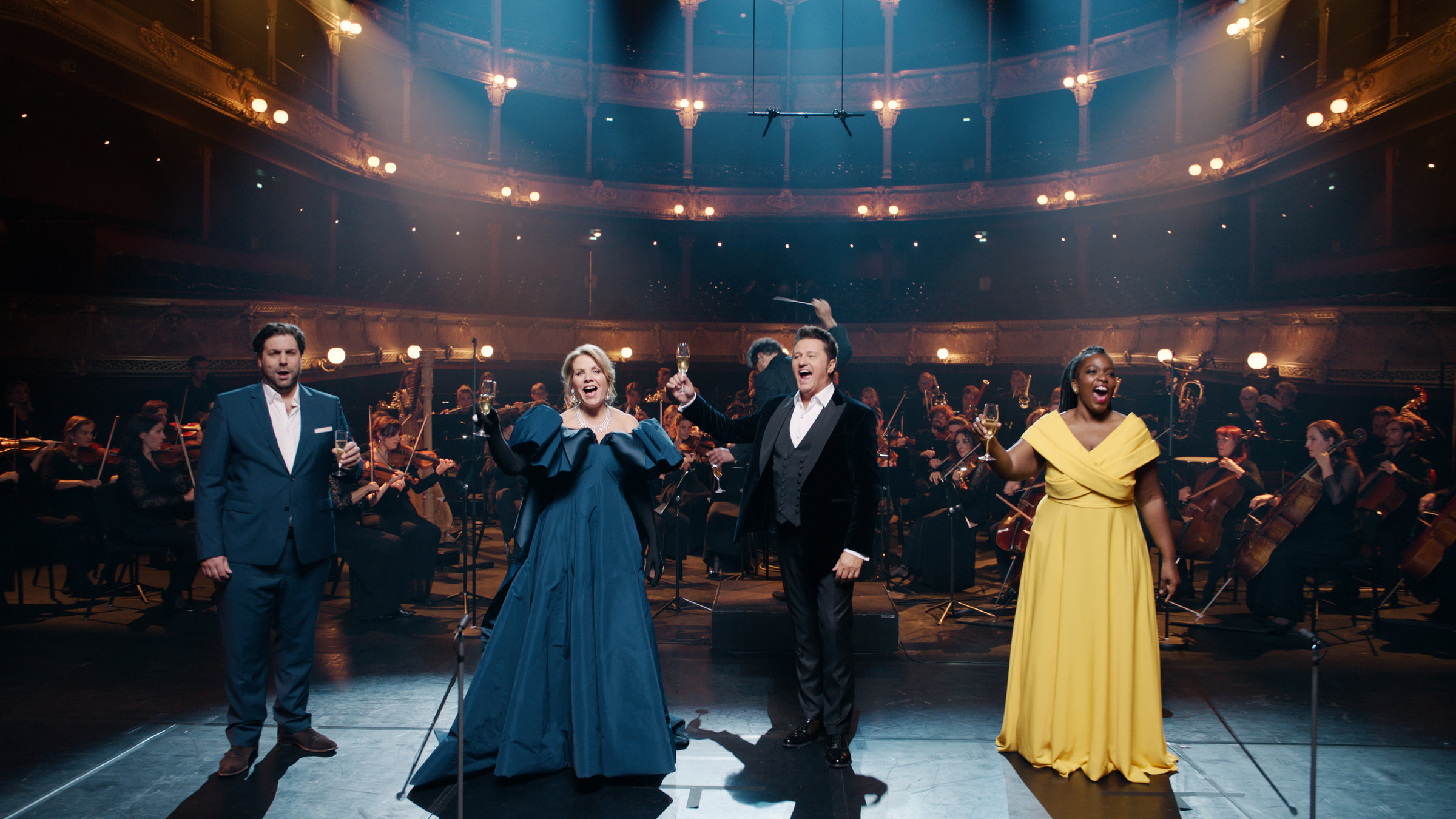 "Musikstadt Paris": v. l. nach rechts auf der Bühne Alexandre Duhamel (Bariton), Renée Fleming (Sopran), Piotr Beczala (Tenor) und Axelle Fanyo (Sopran). Im Hintergrund das Orchester und die Ränge des Theaters.