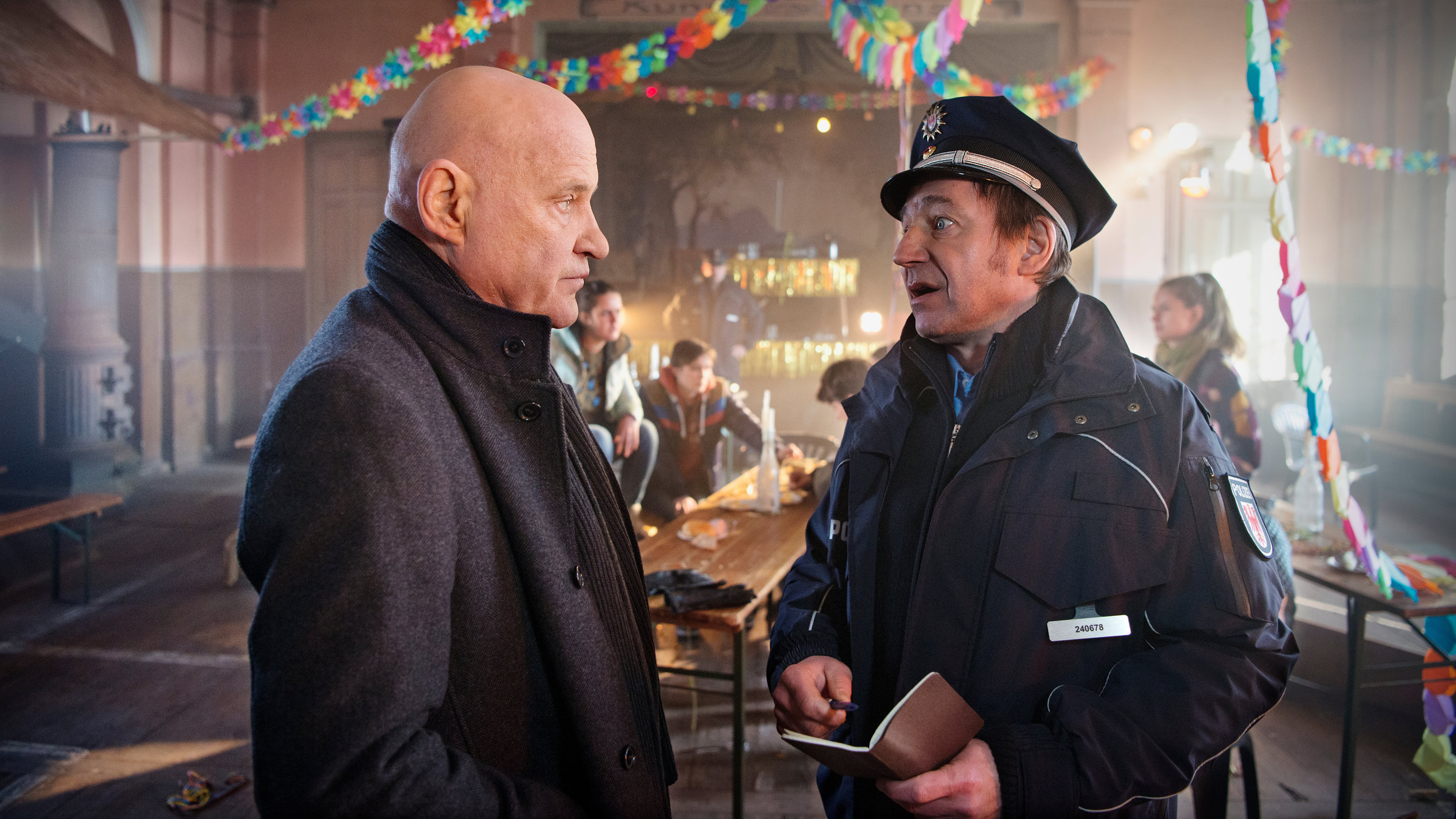 "Spreewaldkrimi - Totentanz": In einem mit Girlanden geschmückten Festsaal redet Fichte (Thorsten Merten) mit Thorsten Krüger (Christian Redl). Im Hintergrund sitzen Jugendliche an Biertischen.