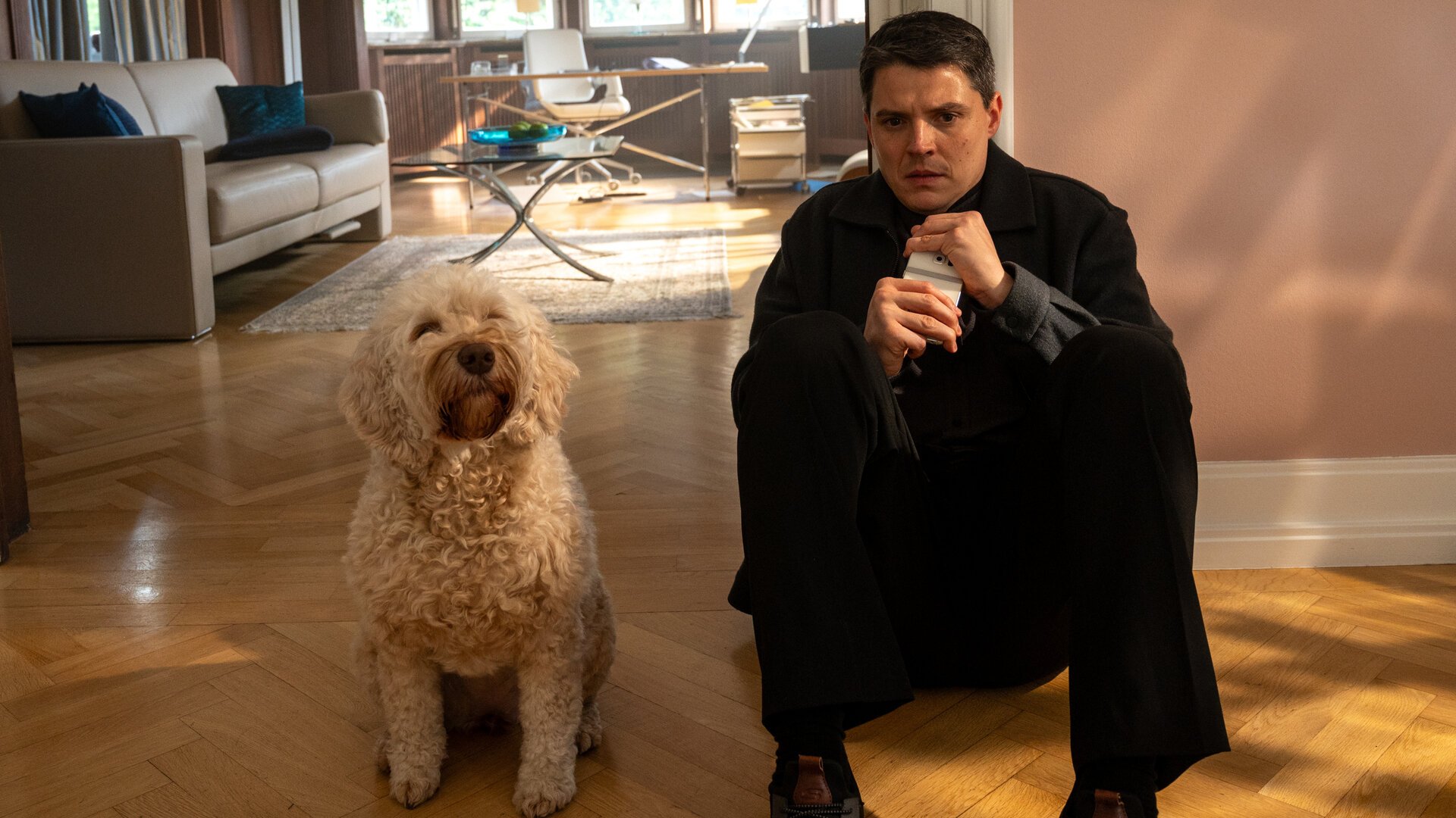 "SOKO Stuttgart - Kaltschnäuzig": Kriminalkommissar Rico Sander (Benjamin Strecker) sitzt in den Räumen einer Therapiepraxis mit dem Rücken an der Wand auf dem Boden. Er krallt sich an seinem Handy fest und schaut verängstigt auf den Boden. Neben ihm sitzt Hündin Bonnie.