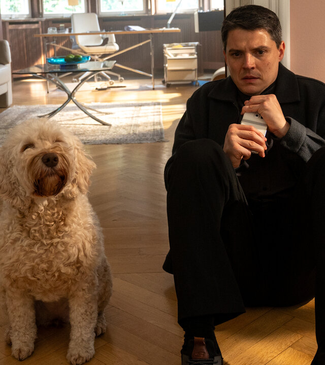 "SOKO Stuttgart - Kaltschnäuzig": Kriminalkommissar Rico Sander (Benjamin Strecker) sitzt in den Räumen einer Therapiepraxis mit dem Rücken an der Wand auf dem Boden. Er krallt sich an seinem Handy fest und schaut verängstigt auf den Boden. Neben ihm sitzt Hündin Bonnie.