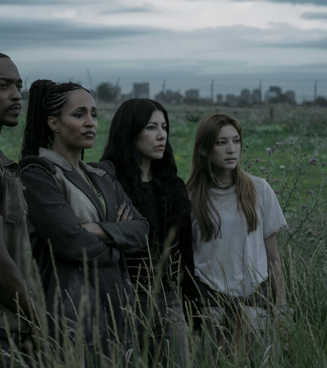 "Twisted Metal - T3STDRV": John (Anthony Mackie), Dollface (Tiana Okoye), Quiet (Stephanie Beatriz) und Mayhem (Saylor Bell Curda) stehen auf einer weiten grünen Wiese mit hohem Gras. Alle blicken mit ernstem Gesichtsausdruck zur Seite in dieselbe Richtung.