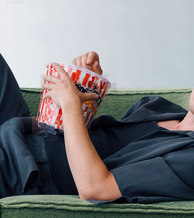 "WTF is Jule?! - What happens online stays online": Maximilian Mundt liegt auf einer grünen Couch und isst Popcorn.