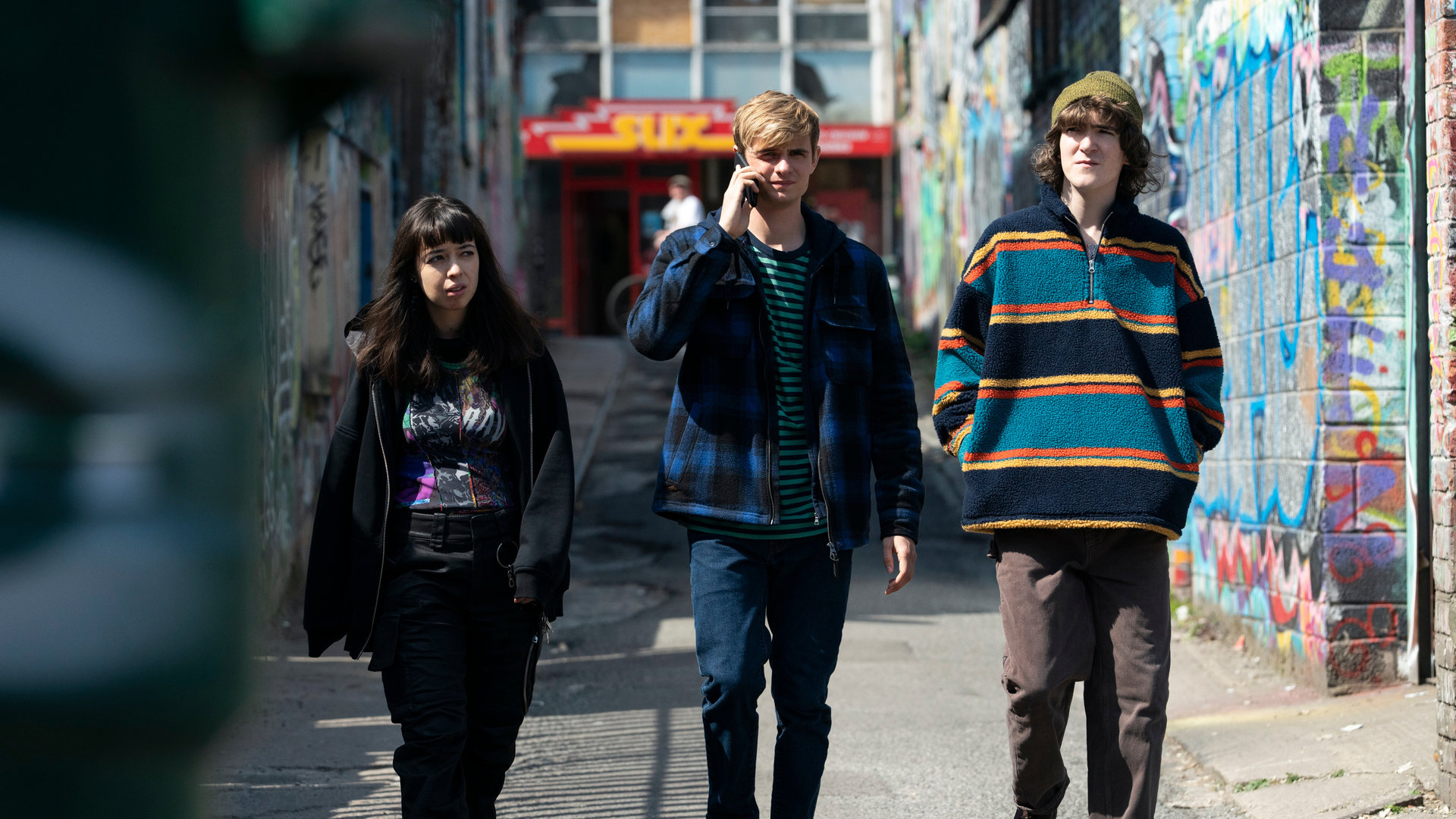 "Alex Rider - Mörder": Kyra (Marli Siu), Alex (Otto Farrant) und Tom (Brenock O'Connor) laufen eine Gasse entlang, während Alex telefoniert.