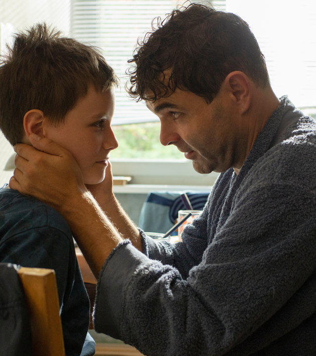 "Das Versprechen": In der Küche steht Fabian (Andreas Döhler) vor seinem Sohn Bendix (Mika Tritto), der auf einem Stuhl sitzt. Fabian umfasst das Gesicht seine Sohnes und sieht ihn eindringlich an. Der Junge erwidert den Blick.