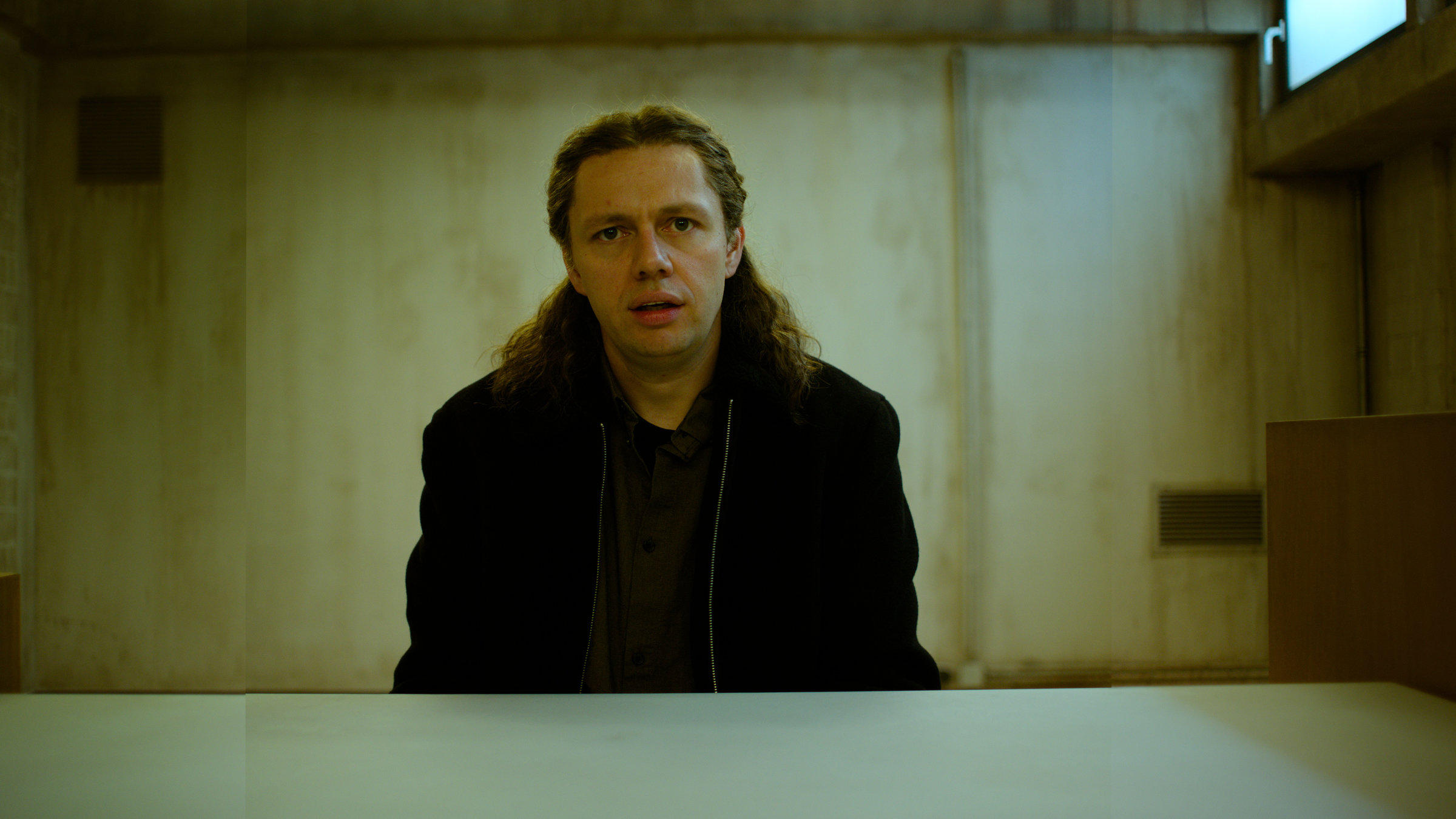 "Parfum - Herzakkord": Daniel "Zahnlos" Sluiter (Christian Friedel) sitzt im Verhörraum der Polizei und stiert nach vorne.