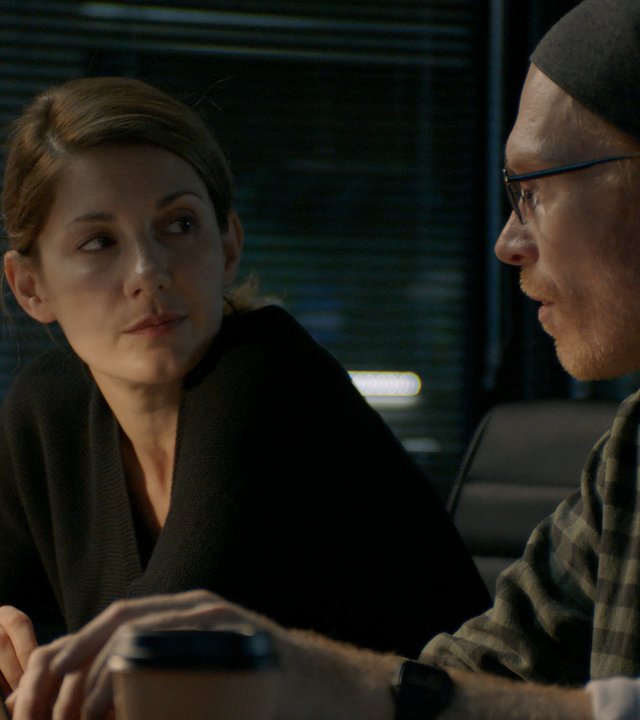 "Hamilton - Undercover in Stockholm (Folge 3)": Kristin Ek (Nina Zanjani) und Birger Hagman (Jörgen Thorsson) sitzen in einem abgedunkelten Raum nebeneinander vor Laptops und unterhalten sich.