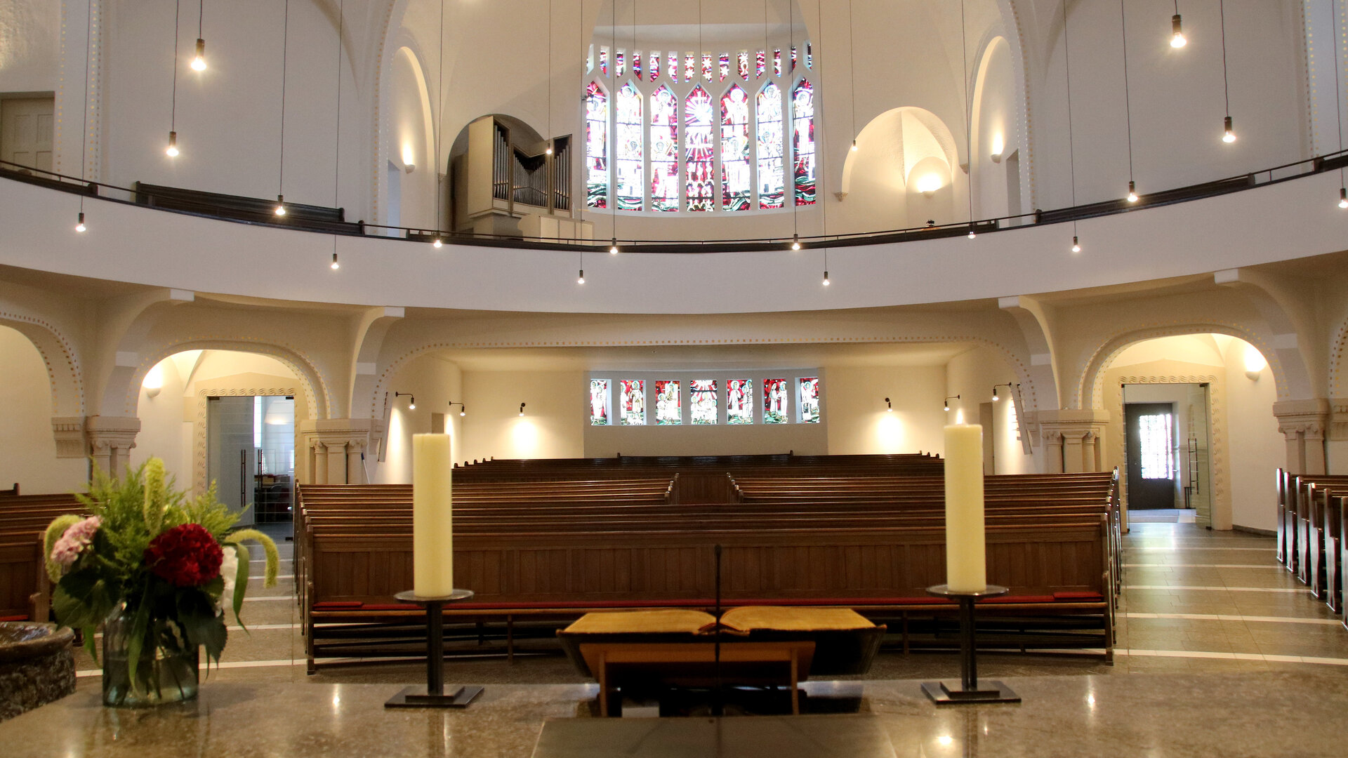 "Evangelischer Gottesdienst - Früchte der Arbeit": In der lichtdurchfluteten Christuskirche in Recklinghausen steht der Altar im Vordergrund, gegenüber fällt Licht durch das bunte Westfenster.