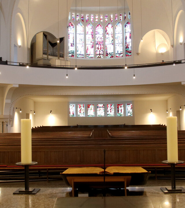"Evangelischer Gottesdienst - Früchte der Arbeit": In der lichtdurchfluteten Christuskirche in Recklinghausen steht der Altar im Vordergrund, gegenüber fällt Licht durch das bunte Westfenster.
