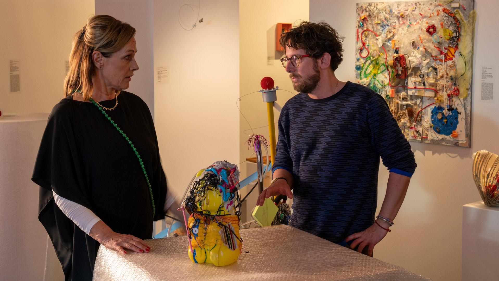 "SOKO Stuttgart - Der gläserne Hund": Vivian Roth (Sabine Bach) steht in der Kunstgalerie an einem Ausstellungstisch. Auf dem Tisch thront eine abstrakte Kunststoffskulptur in leuchtenden Farben. Auf der anderen Seite des Tisches steht Oliver Hagen (Marian Meder). Die beiden schauen sich ernst an.
