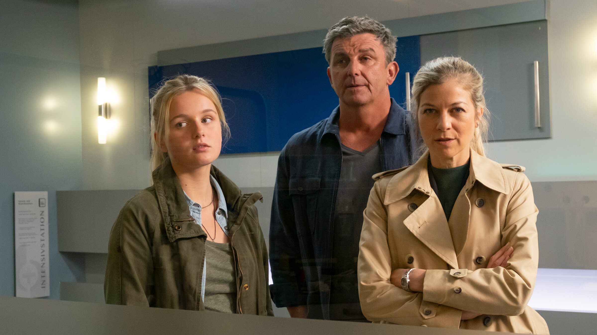 "Der Bergdoktor - Paradies (2)": Martin (Hans Sigl), Josie (Lieselotte Voß) und Karin Bachmeier (Hilde Dalik) stehen nebeneinander im Krankenhaus und blicken durch ein Fenster geradeaus.