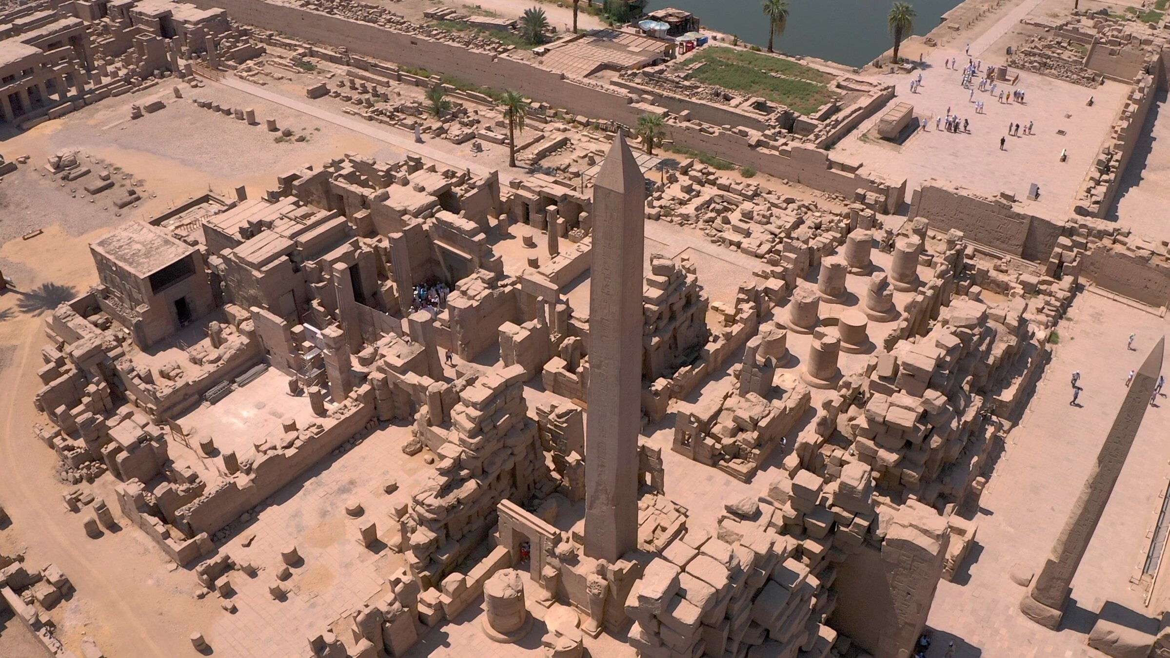 "Terra X: Ungelöste Fälle der Archäologie - Technik": Luftaufnahme des altägyptischen Tempels von Karnak, von dem diverse Bauten, ein kleiner Teil eines künstlichen Sees, sowie ein großer Obelisk zu sehen sind.