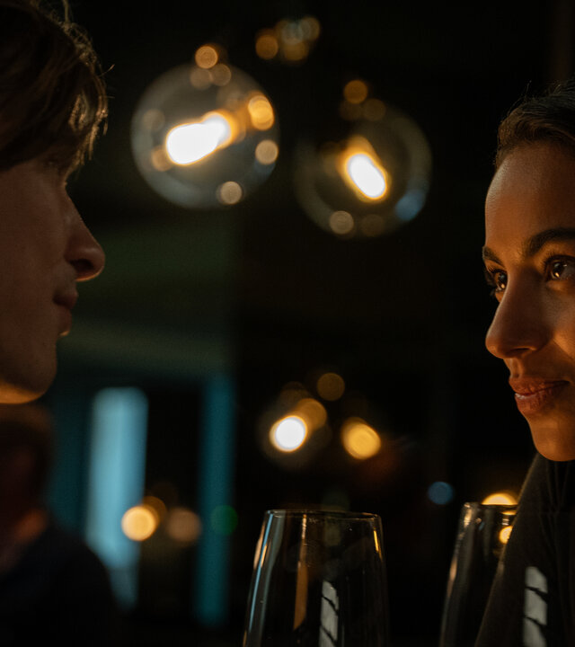 "Crystal Wall - Eifersucht": Dita (Gizem Emre) und Nicolas Dardenne (Gustav Schmidt) sitzen sich in einem abgedunkeltem Restaurant gegenüber und schauen sich tief in die Augen.
