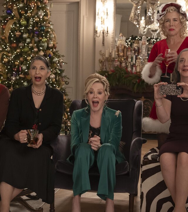 "Hacks - Das Vegas-Weihnachtsspektakel": In festlicher Kleidung sitzen Damien (Mark Indelicato), Josefina (Rose Abdoo), Deborah (Jean Smart) und Avas Mutter Nina (Jane Adams) lachend nebeneinander in einem festlich geschmückten Wohnraum. Hinter ihnen steht Bürgermeisterin Mayor Jo (Lauren Weedman) im Santa-Kostüm. An der Seite steht ein großer Weihnachtsbaum.