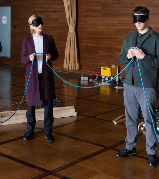 "SOKO Stuttgart - Teams": Michael Kaiser (Karl Kranzkowski), Martina Seiffert (Astrid M. Fünderich), Rico Sander (Benjamin Strecker) und Nele Becker (Nina Siewert) befinden sich in einem großen holzvertäfelten Raum. Sie stehen mit verbundenen Augen im Kreis und halten gemeinsam ein Seil in den Händen. Der Teambuilding-Coach Franz Scherer (Gábor Biedermann) schaut sie erwartungsvoll an. Im Hintergrund sieht man Teile einer noch nicht fertiggestellten Kugelbahn.