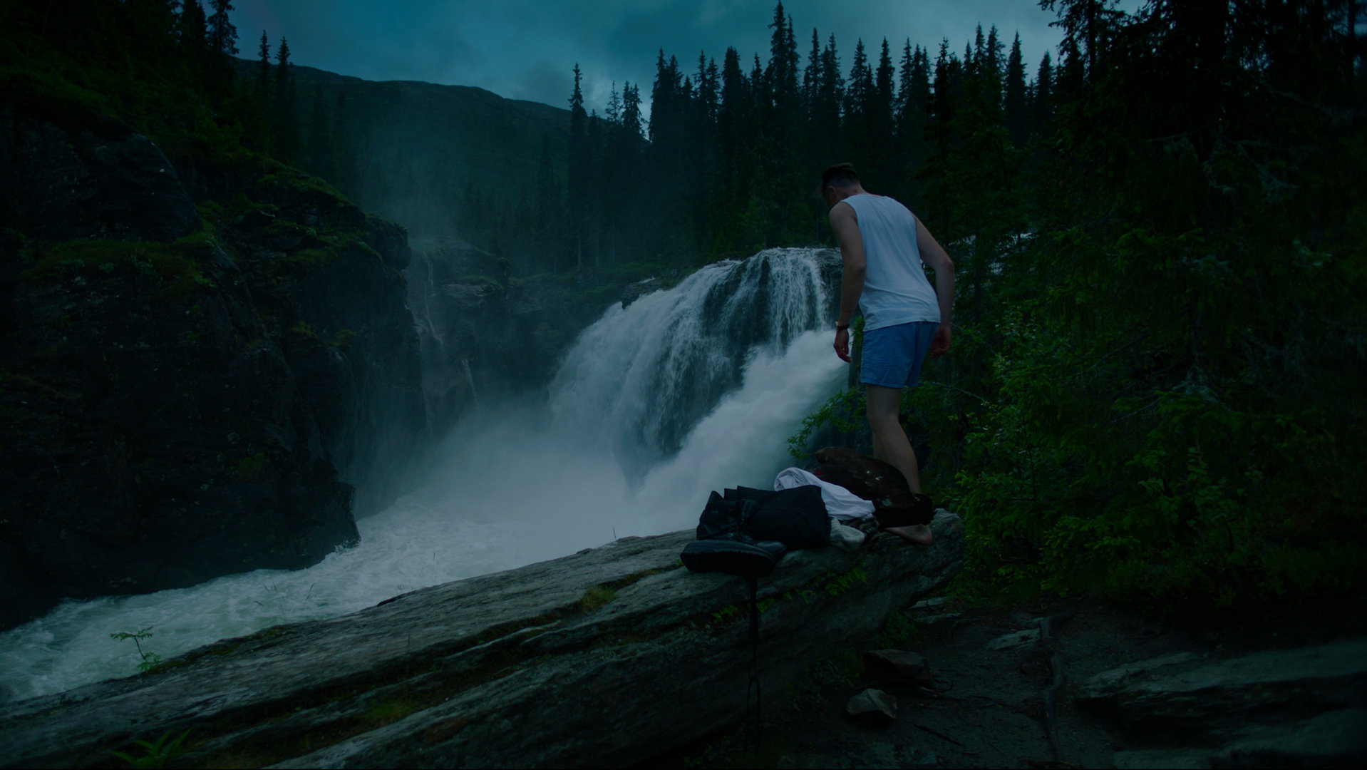 "Exit - Abgesang": William (Pål Sverre Hagen) steht in Unterwäsche auf einer Klippe vor einem Wasserfall und schaut nach unten.