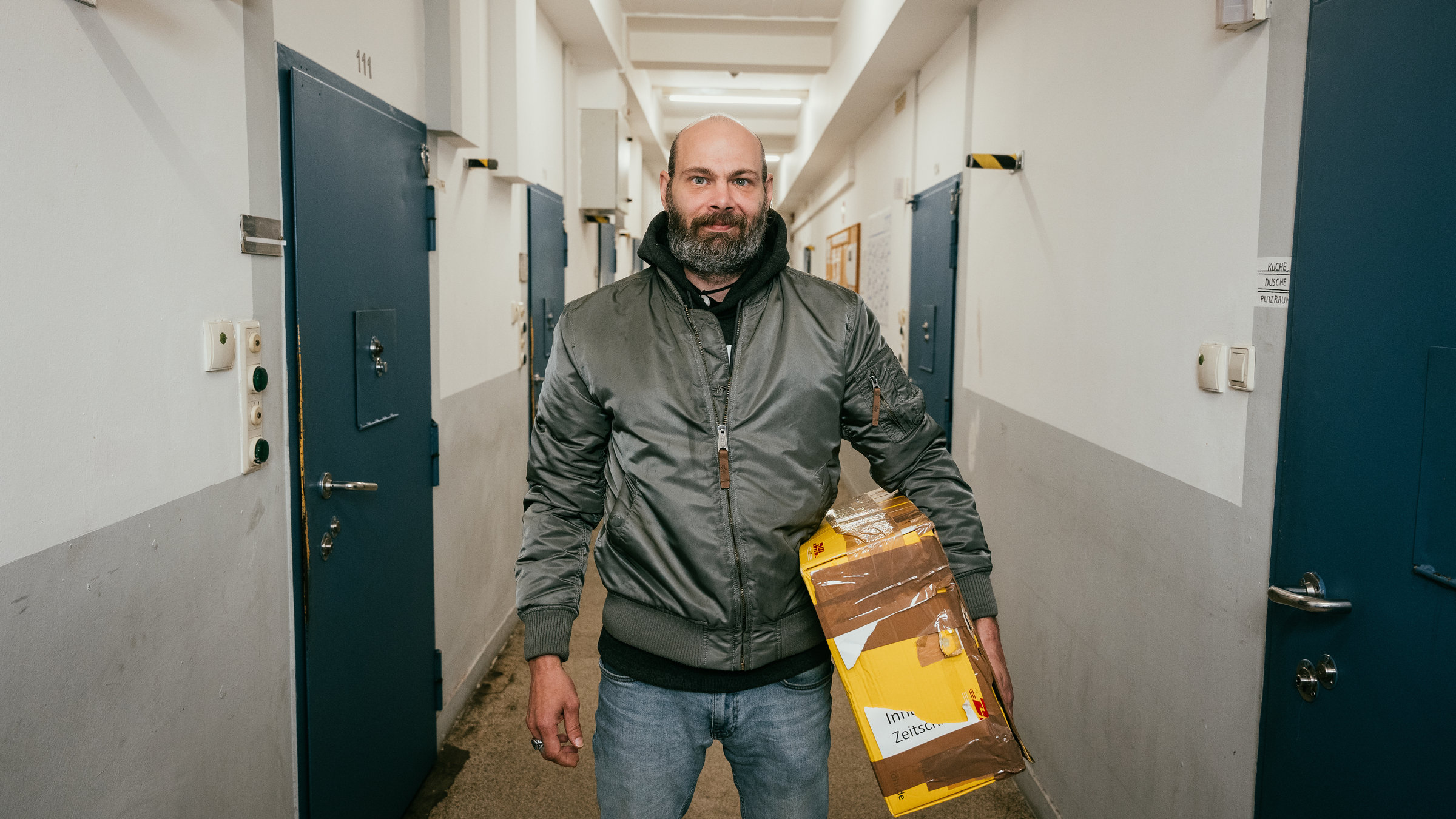 "37°Leben - Mein neues Leben nach der Haft": Thorsten steht im Gefängnisflur und schaut in die Kamera. Er trägt ein Paket unter dem Arm.