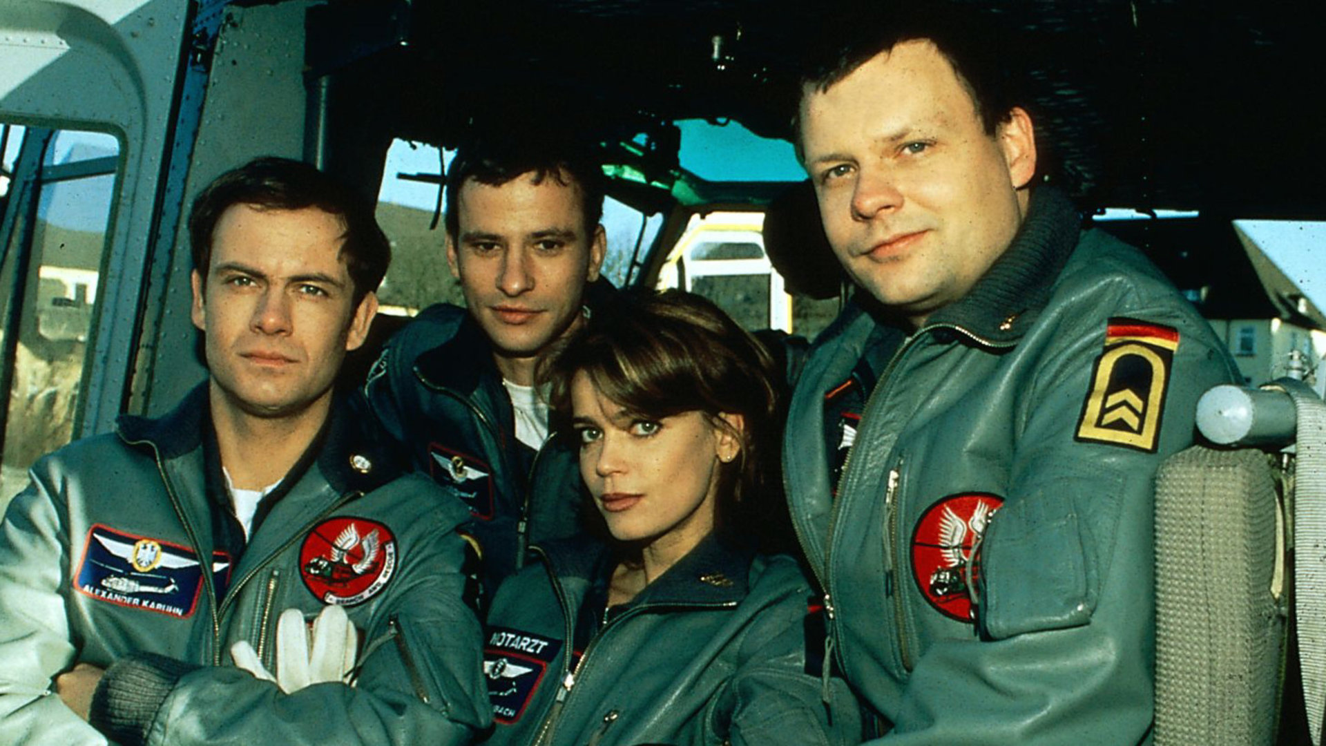 "Die Rettungsflieger - In Panik": Alexander Karuhn (Matthias Leja), Max Westphal (Frank Stieren), Maren Maibach (Gerit Kling) und Thomas Asmus (Ulrich Bähnk) stehen zusammen an einem Rettungshubschrauber und blicken in die Kamera.