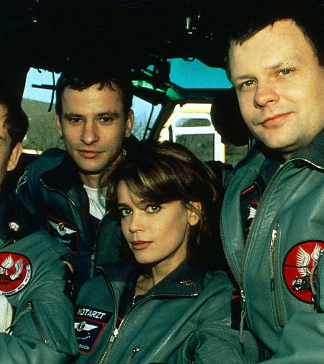 "Die Rettungsflieger - In Panik": Alexander Karuhn (Matthias Leja), Max Westphal (Frank Stieren), Maren Maibach (Gerit Kling) und Thomas Asmus (Ulrich Bähnk) stehen zusammen an einem Rettungshubschrauber und blicken in die Kamera.