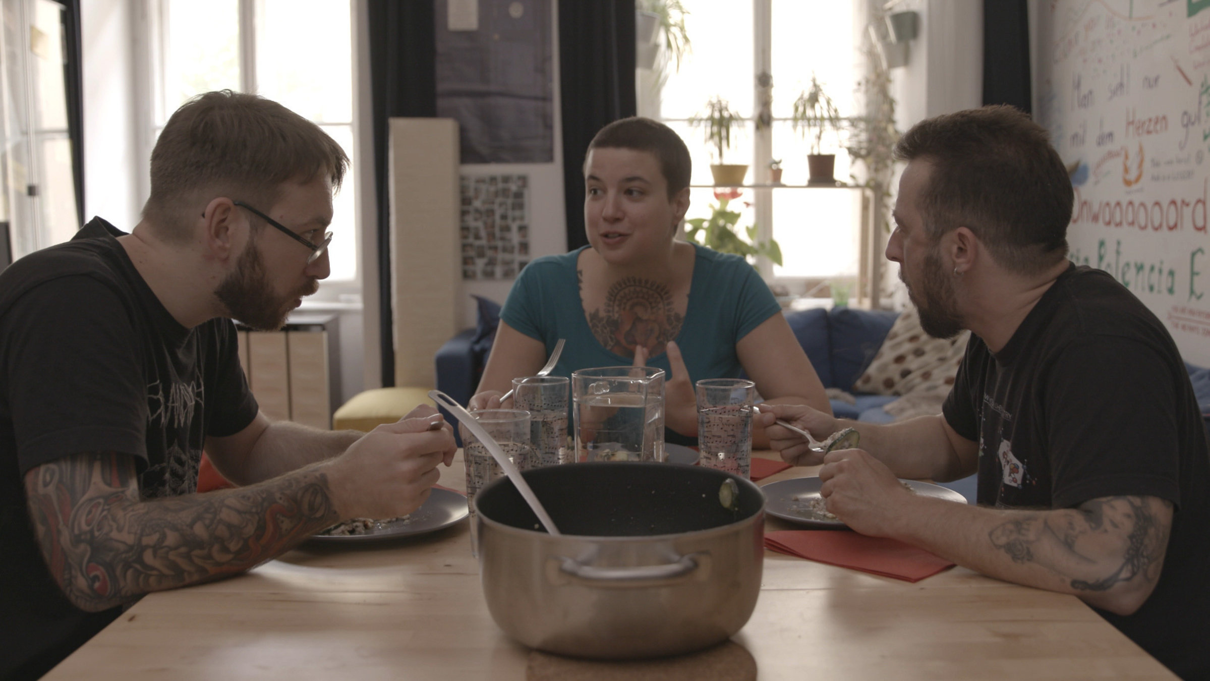 "Die Erfindung der Liebe": Iris, Robert und Andree zusammen in der Wohnung, beim Essen und Zusammensein. Sie gehören zur "Polykül"-Gruppe (ca. 8 Personen, die Freundschaft und Beziehung "teilen" bzw. zu bestimmten Regeln miteinander auch intim agieren).