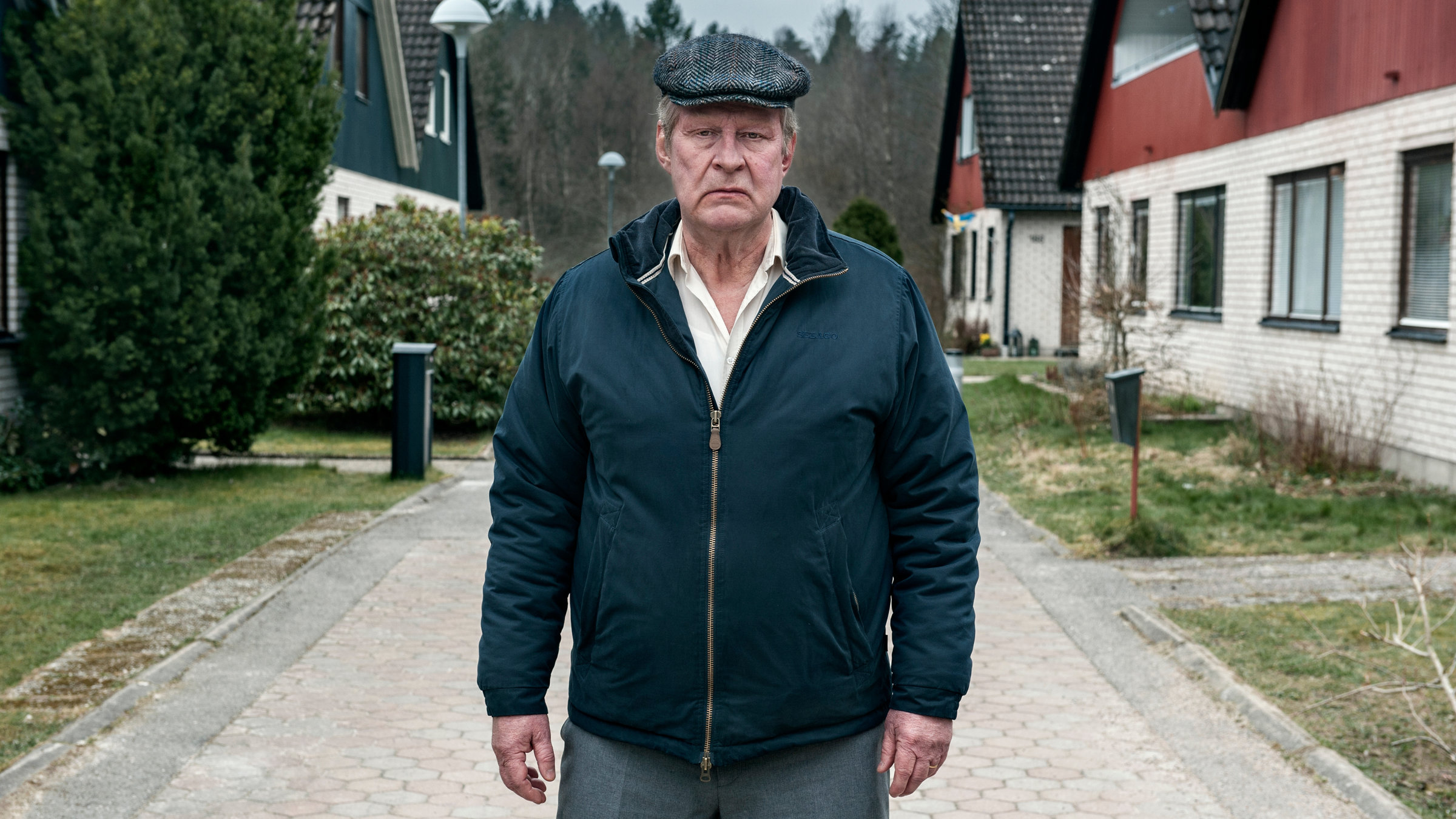 "Ein Mann namens Ove": Ove (Rolf Lassgård) steht mit ernstem Gesicht auf einem gepflasterten Weg in seiner Wohnsiedlung.