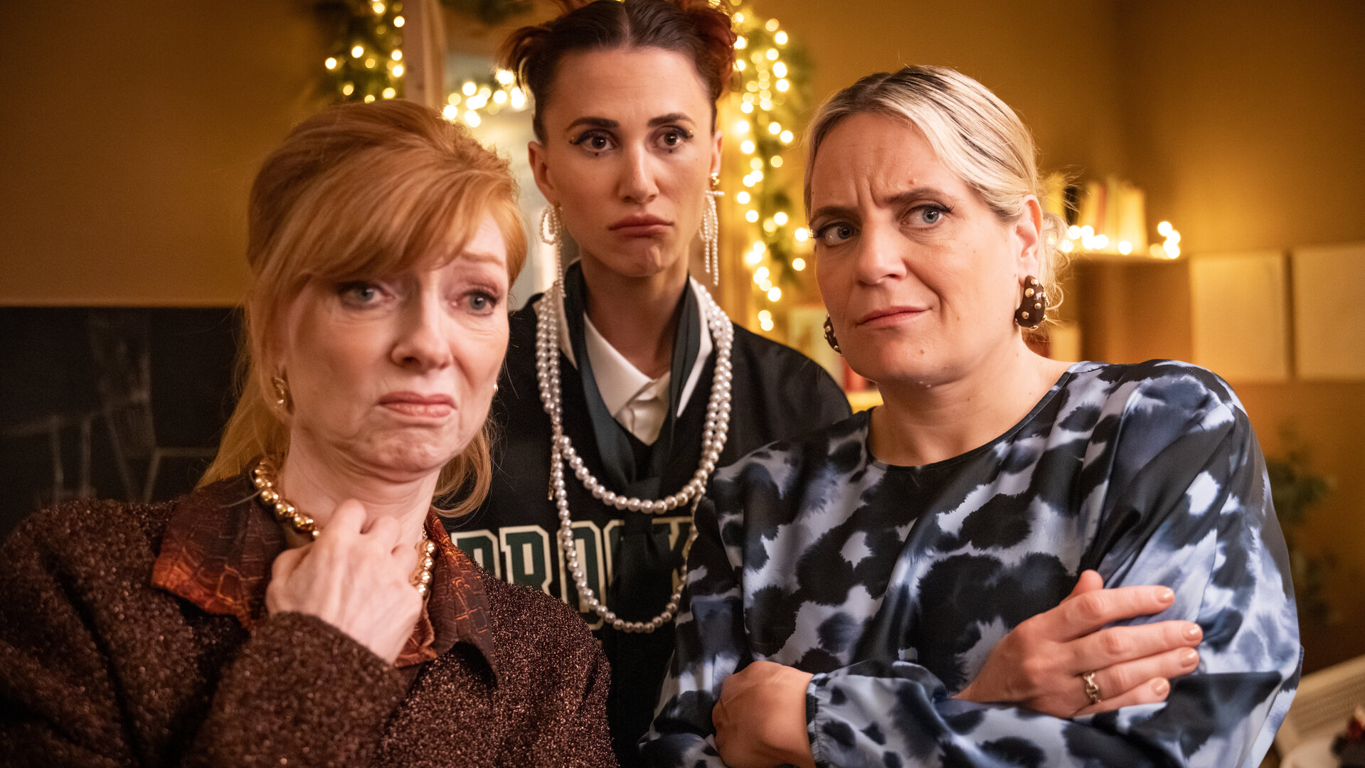 "Single Bells - Only Losers for Annie? - Damien (I)": Annie (Marleen Merckx), Daffy (Lize Feryn), Babs (Ruth Beeckmans) stehen in einem Raum und schauen sehr skeptisch.