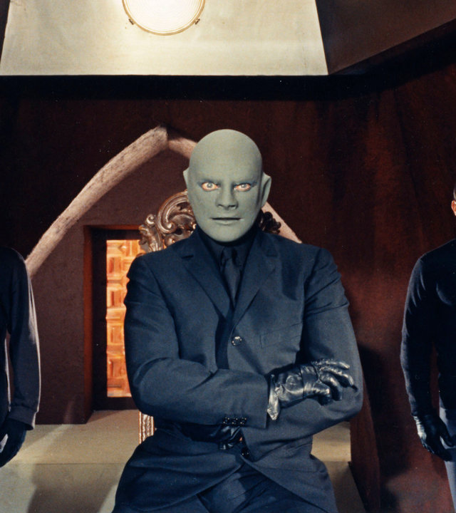 "Fantomas bedroht die Welt": Fantomas (Jean Marais) sitzt mit verschränkten Armen in einer Höhle, während Richard (Hubert de Lapparent) und der Mafiaboss (Guy Delorme) neben ihm Wache stehen.