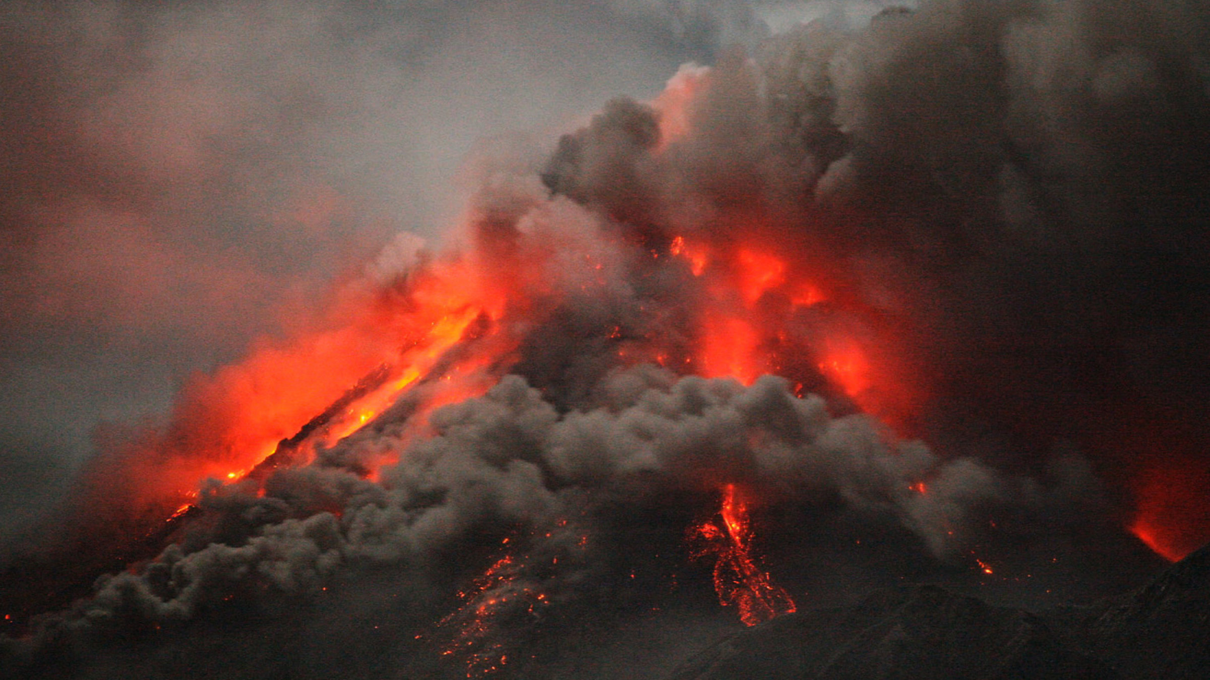 "Terra X: Leben auf dem Vulkan": Ausbrechender Vulkan. Rot-gelbe Lavaströme werden zum Teil von schwarz-grauen Rauchwolken verdeckt.