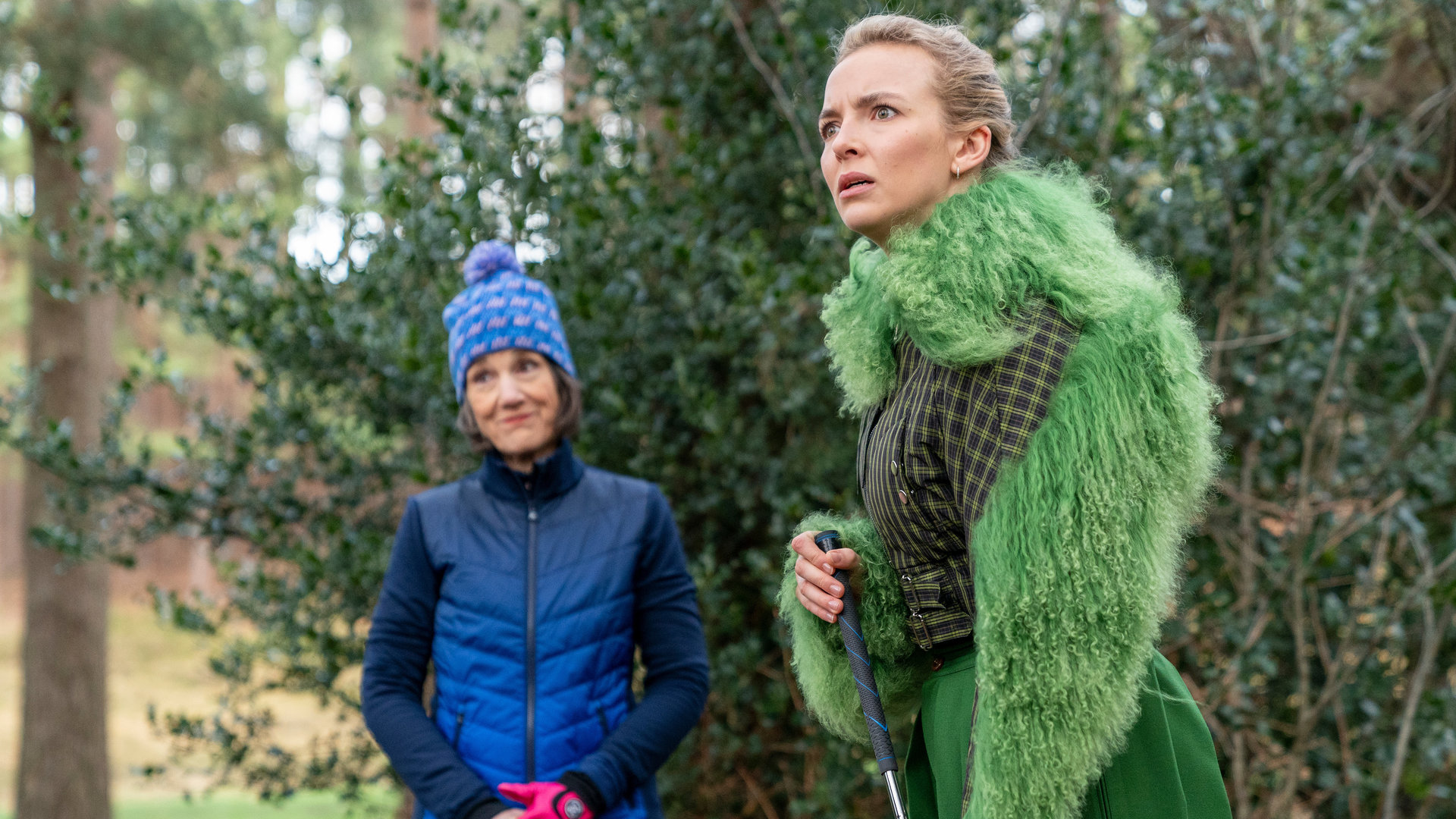 "Killing Eve - Er schreit förmlich danach, umgebracht zu werden": Villanelle (Jodie Comer) und Dasha (Harriet Walter) stehen mit Golfausrüstung in einem Wald und halten nach etwas Ausschau.